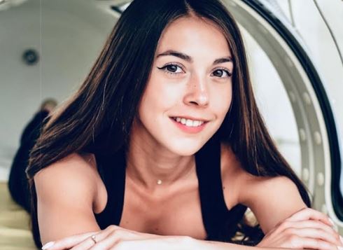 Brunette woman inside of a mild hyperbaric chamber looking at the camera.
